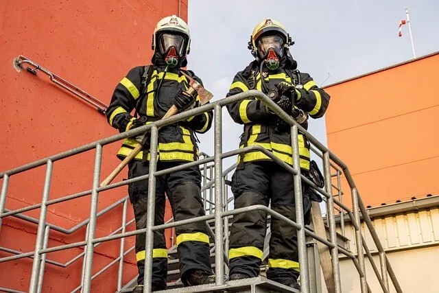 Two firefighters wearing breathing apparatus on an outdoor staircase